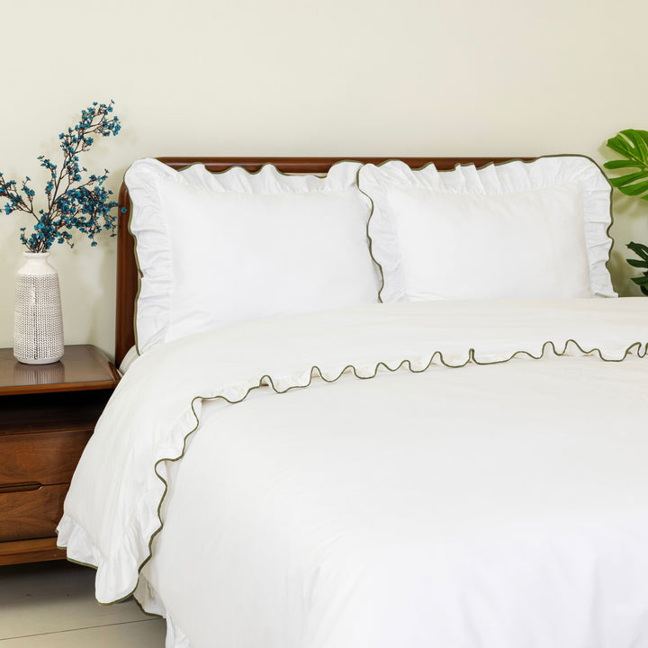 White ruffle duvet cover and pillow shams with green trim on a bed